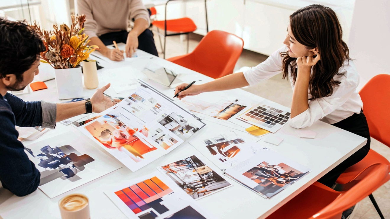 Design team developing concepts around a table with orange chairs and materials